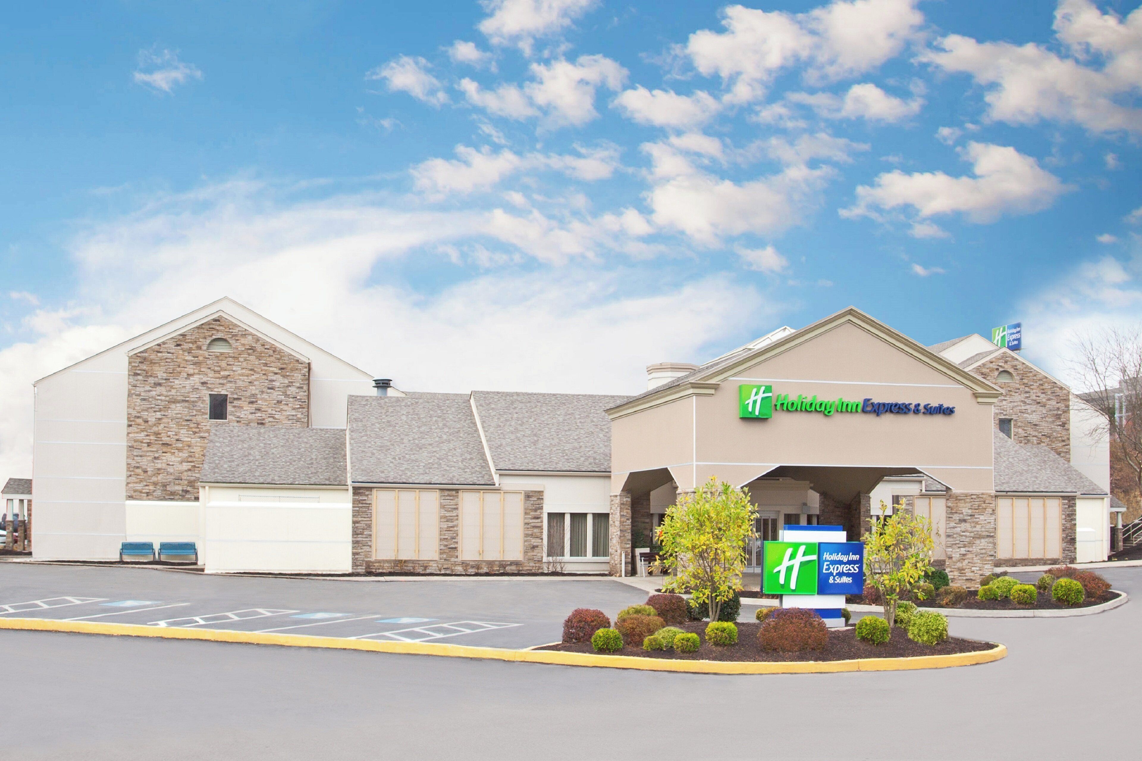 A Holiday Inn Express & Suites building with a stone facade, a covered entrance, and a parking lot with marked spaces.