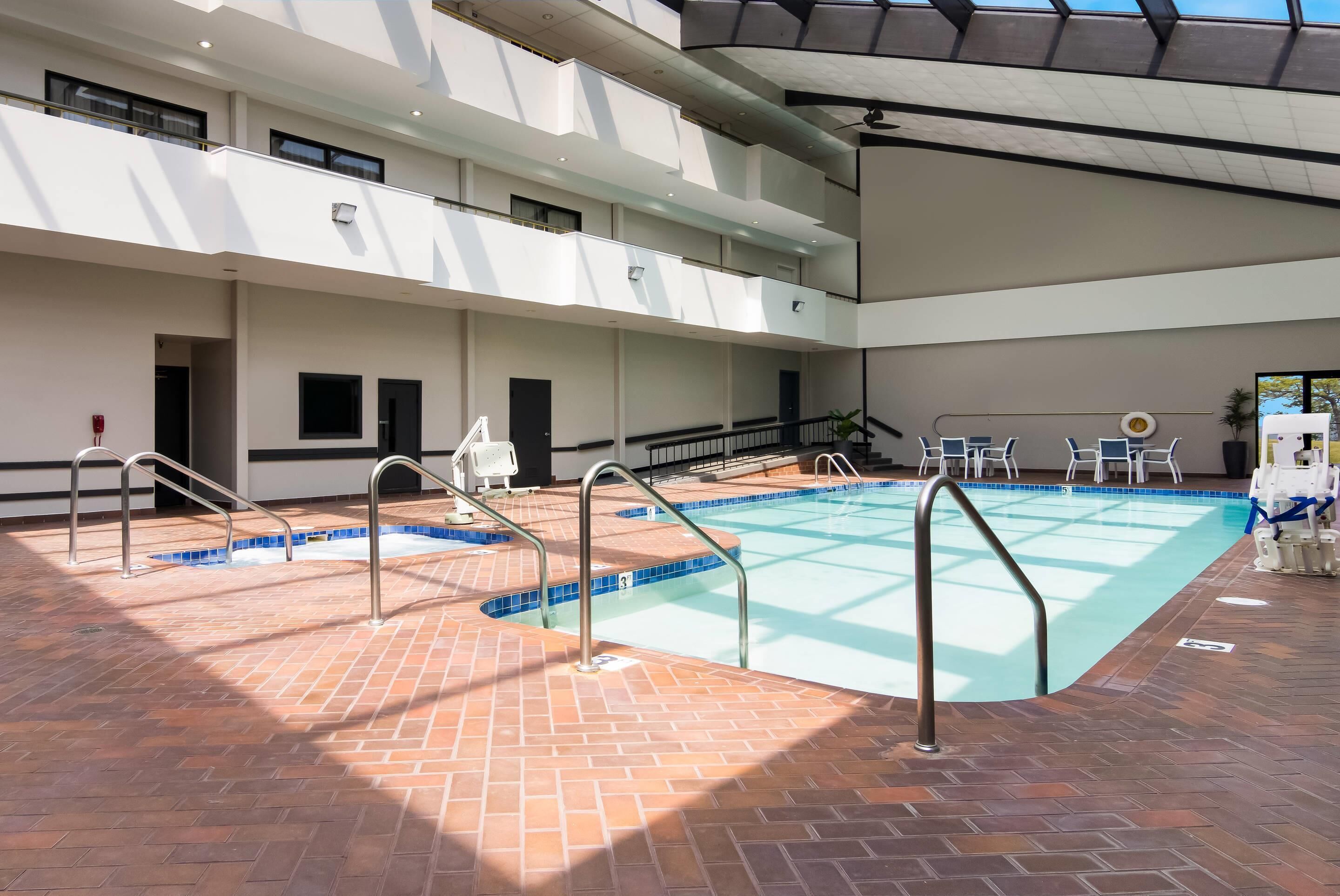 Une piscine intérieure à plusieurs niveaux, avec un sol en briques, des rampes en métal et une eau d’un bleu cristallin.