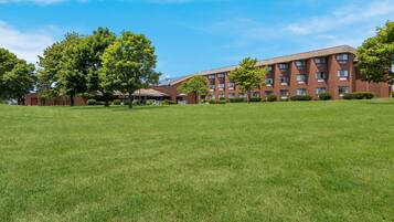A multi-story brick building with a flat roof, surrounded by well-maintained grass lawns and trees.