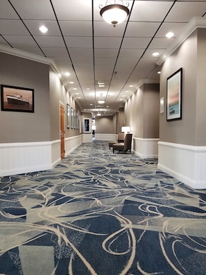 Stylish corridor with framed artwork, a comfortable chair, and a wooden door.