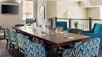 A conference room with a long table, chairs, and a TV on the wall.
