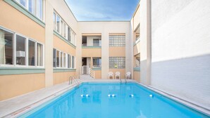 Una piscina con agua azul cristalina, rodeada de paredes color beige y barandillas blancas.