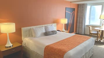 A hotel room with a large bed, two bedside lamps, a nightstand, a chair, and a table.