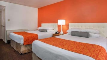 Habitació d'hotel amb dos llits, cadascun amb capçalera blanca i roba de llit taronja. Hi ha una tauleta de nit amb una làmpada entre els llits.