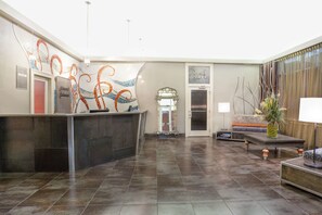 Eine Lobby mit einer Rezeption, einer Couch, einem Couchtisch und einer dekorativen Vase.