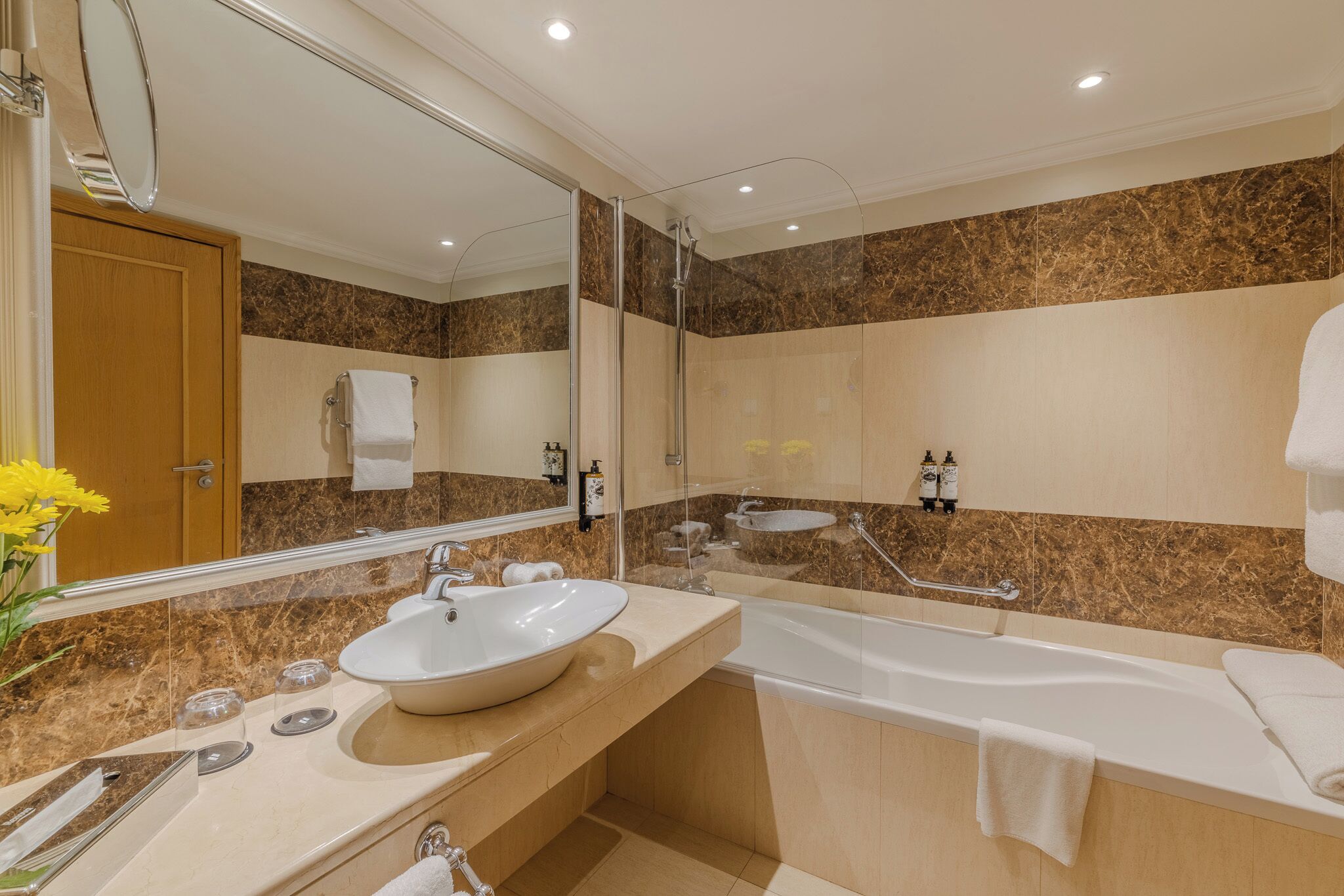 A modern bathroom with a large mirror, a sink, a bathtub, and a shower.