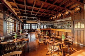 A bar area with wooden furniture, a bar counter, and shelves with bottles. - Pestana Carlton Madeira Ocean Resort Hotel (Funchal)