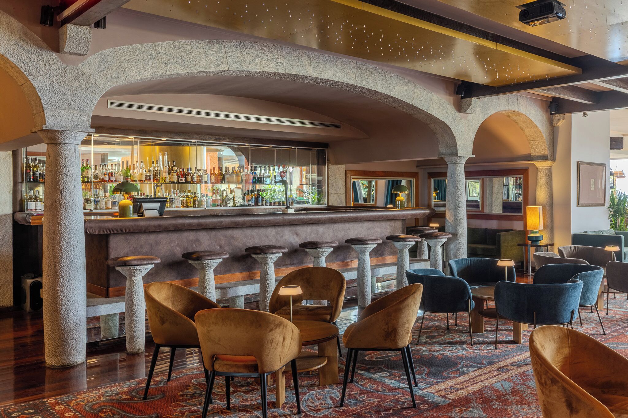 A bar area with a stone column structure, bar stools, and a variety of seating options including chairs and sofas.