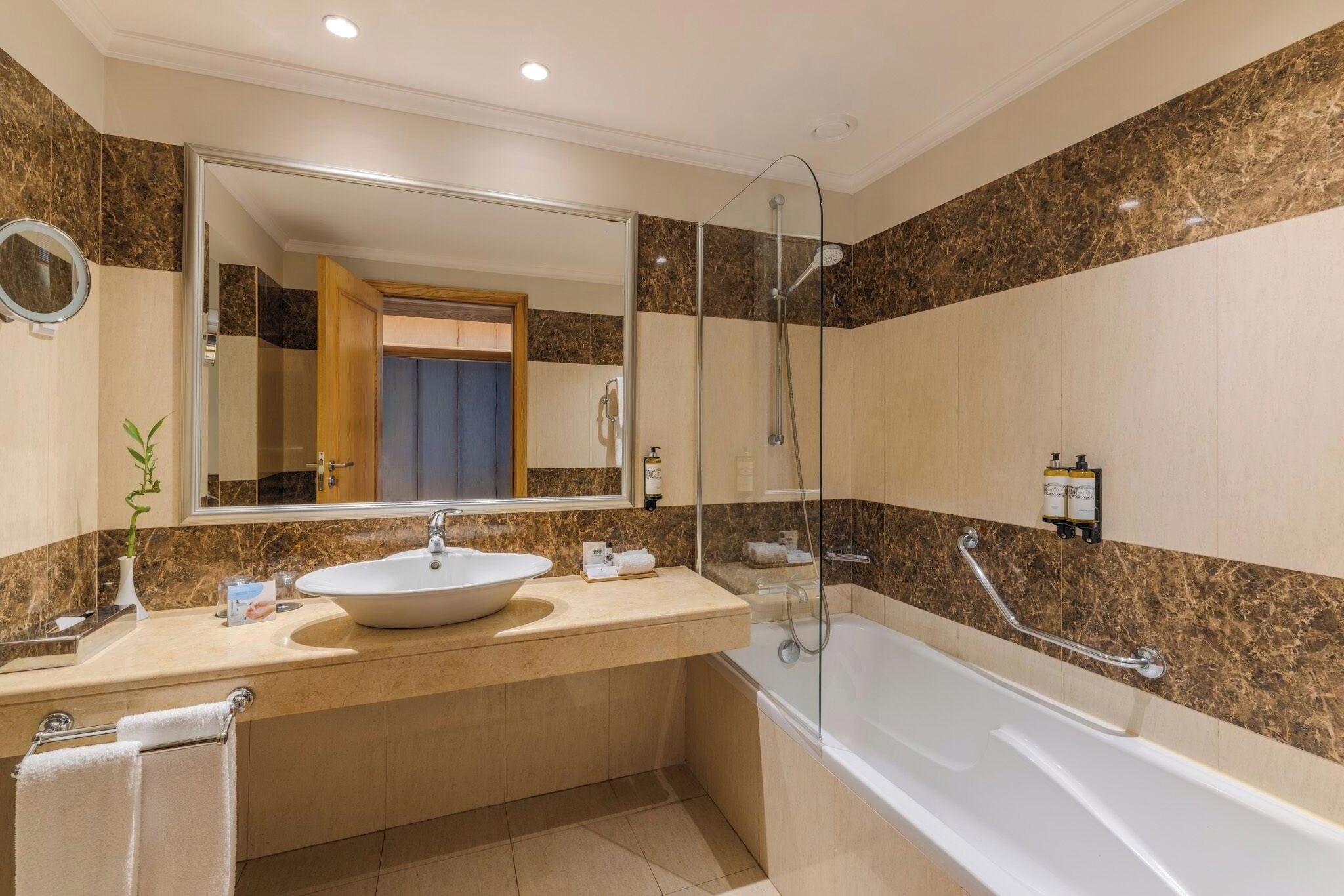 A modern bathroom with a large mirror, a sink, a bathtub, and a shower.