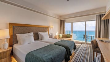 Une chambre d’hôtel avec deux lits, un bureau, une chaise et une vue sur l’océan.