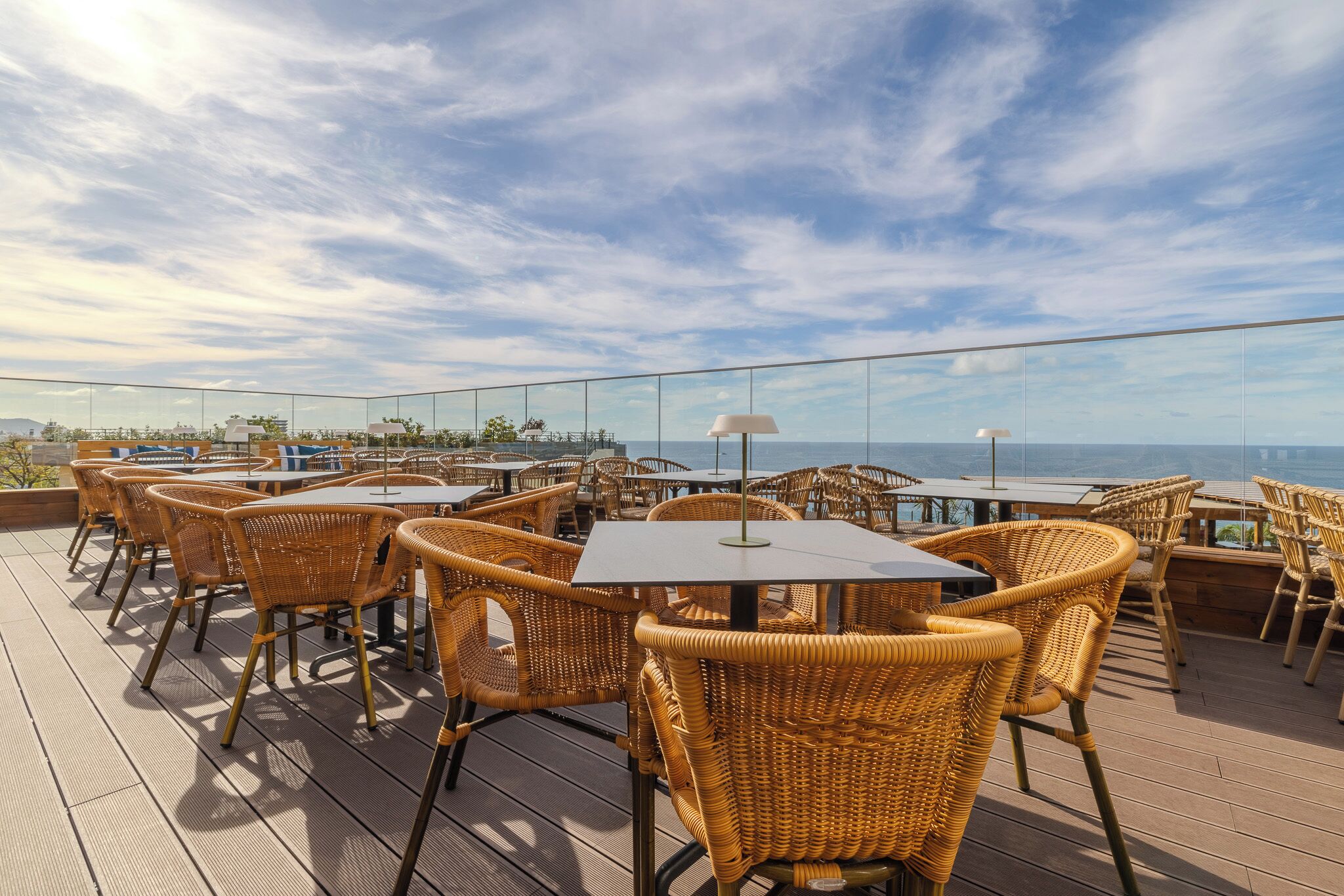 Une terrasse sur le toit, dotée de chaises et de tables en osier, offrant une vue imprenable sur la côte.