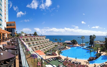 A resort with a large pool, outdoor seating, and a view of the ocean.