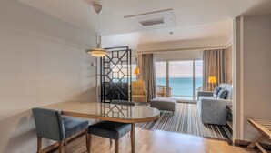 Une chambre d’hôtel moderne dotée d’un coin repas, d’un canapé et offrant une vue sur la mer.