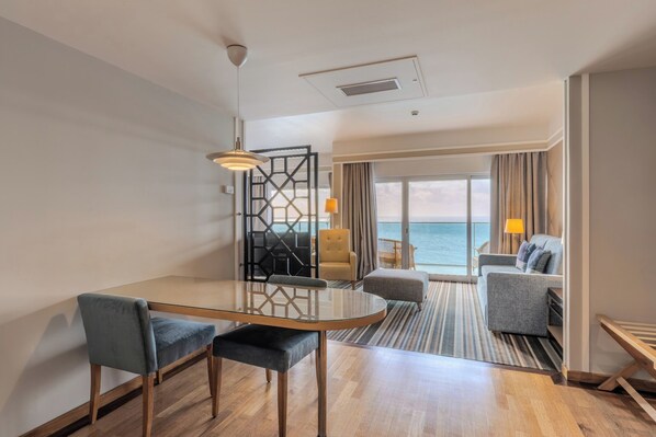 A modern hotel room with a dining area, a sofa, and a view of the sea. - Pestana Carlton Madeira Ocean Resort Hotel (Funchal)