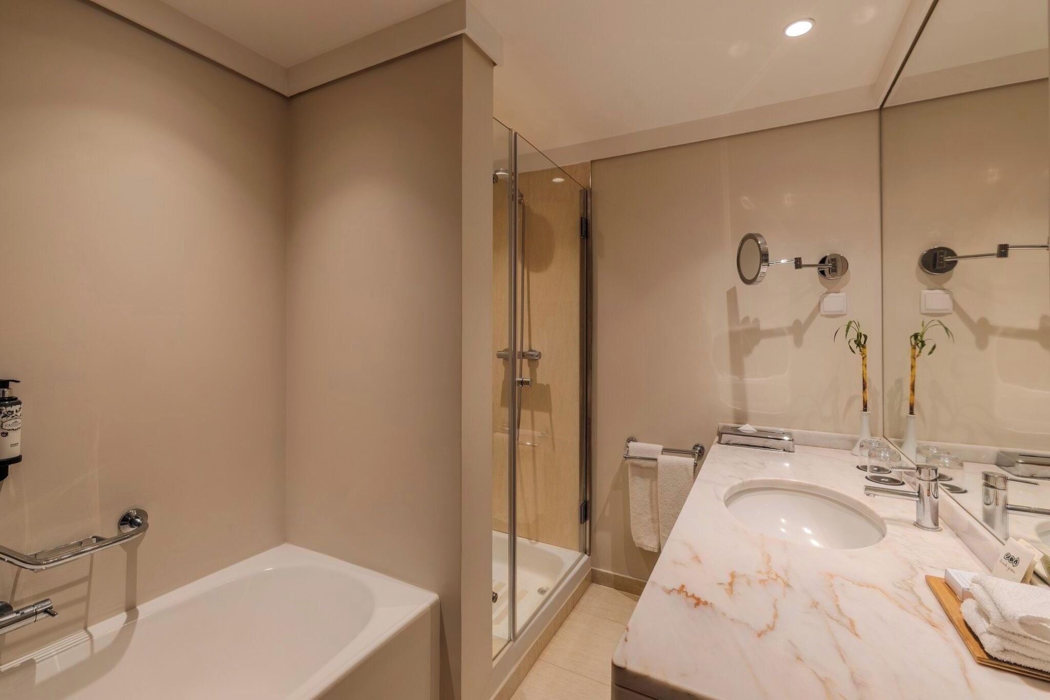A modern bathroom with a bathtub, a glass-enclosed shower, and a marble vanity.