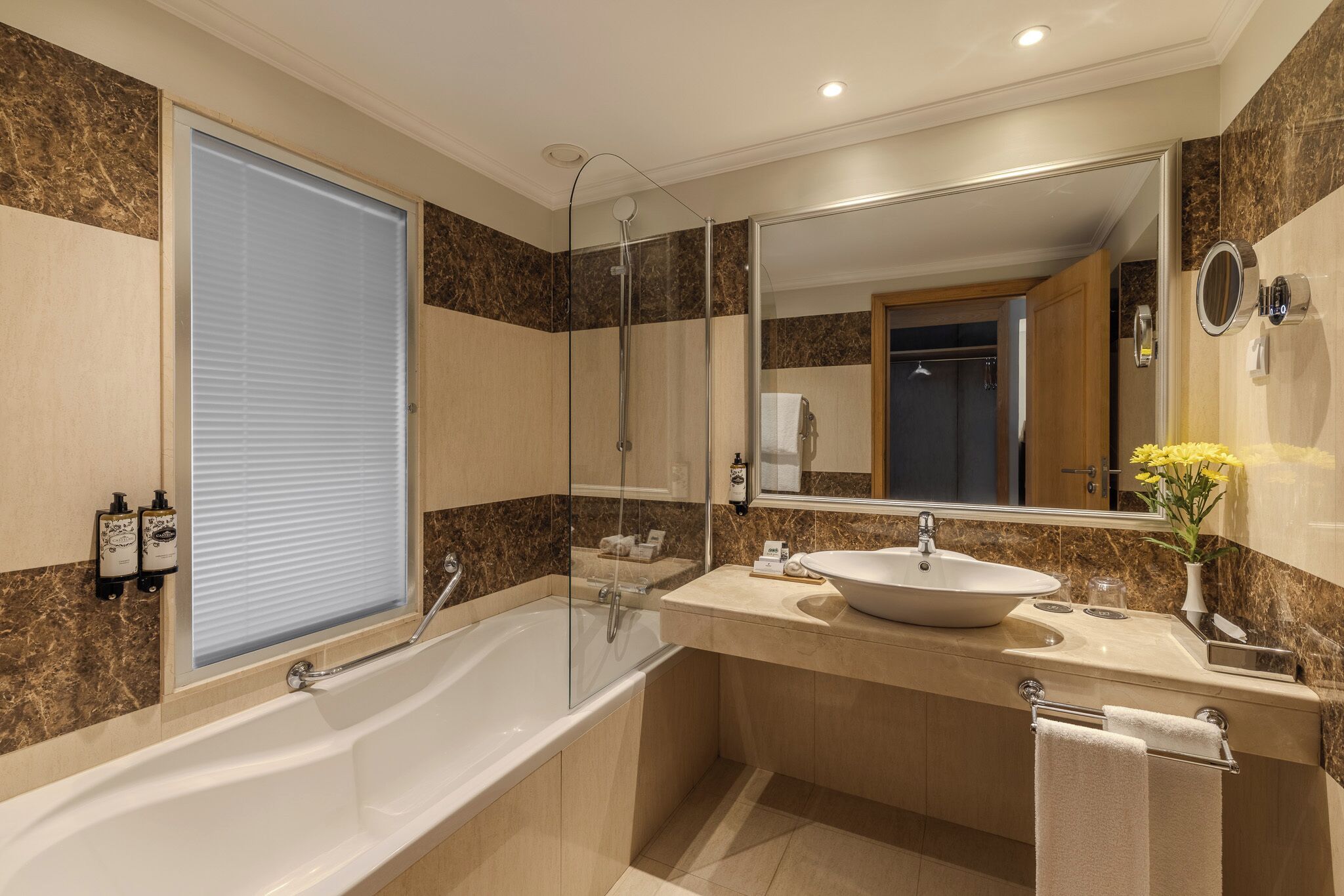 Une salle de bain moderne dotée d’une grande baignoire, d’un meuble-lavabo à deux vasques, d’une cabine de douche en verre et d’un grand miroir.