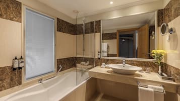 Une salle de bain moderne dotée d’une grande baignoire, d’un meuble-lavabo à deux vasques, d’une cabine de douche en verre et d’un grand miroir.