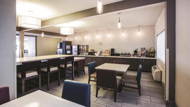 A modern hotel lobby with a bar, seating area, and a kitchenette. - La Quinta Inn by Wyndham Indianapolis North at Pyramids (Indianapolis)