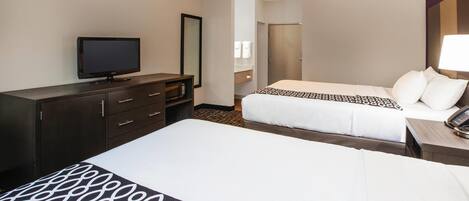 Habitación de hotel con dos camas, un televisor, un aparador y un baño visible a través de una puerta abierta.