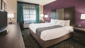 A hotel room with a large bed, two bedside tables with lamps, a desk with a computer, and a TV. - La Quinta Inn by Wyndham Indianapolis North at Pyramids (Indianapolis)