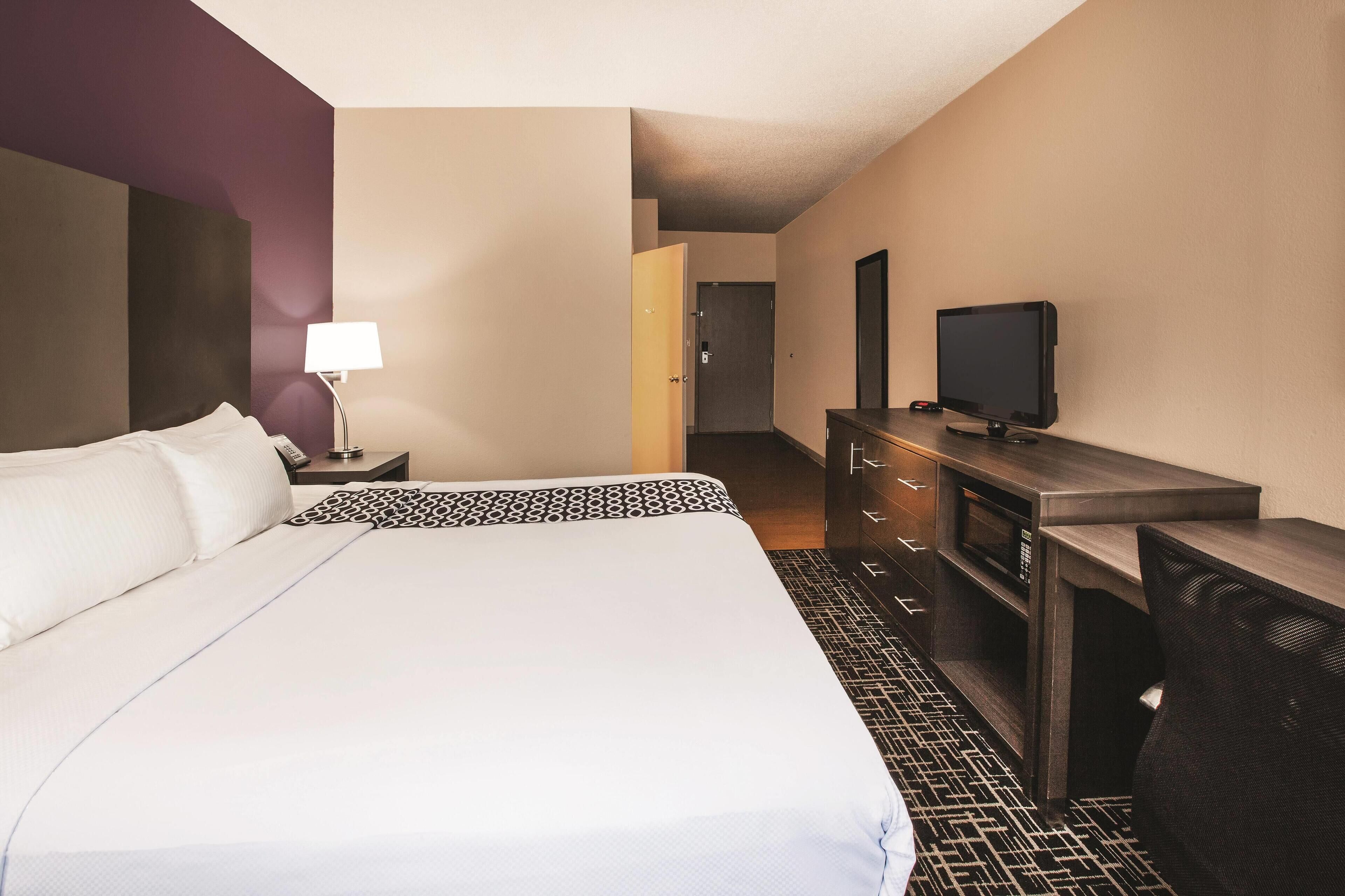 Une chambre d’hôtel avec un grand lit, un bureau équipé d’une télévision, d’une lampe et d’un four à micro-ondes.