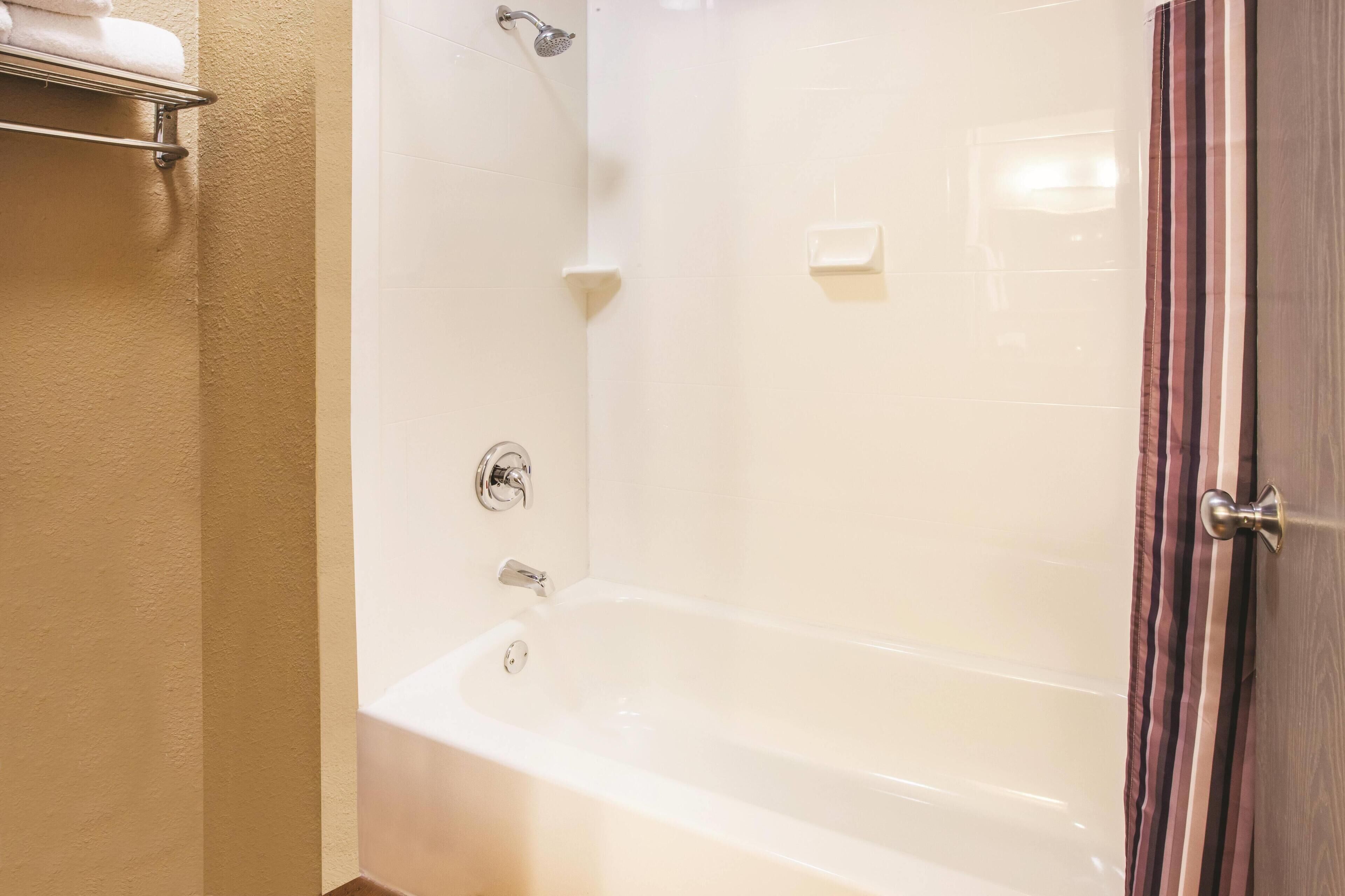 A bathroom with a bathtub, a towel rack, and a showerhead.