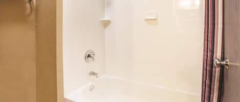 A bathroom with a bathtub, a towel rack, and a showerhead.