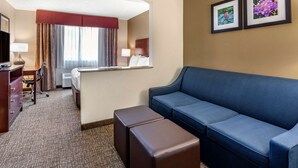 A hotel room with a blue sofa, a desk with a chair, a bed with a red headboard, and two framed pictures on the wall. - Comfort Inn Kelso - Longview (Kelso)