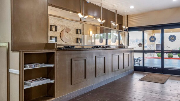 A reception area with a wooden counter, shelves with magazines, and a view through the glass door. - Comfort Inn Kelso - Longview (Kelso)