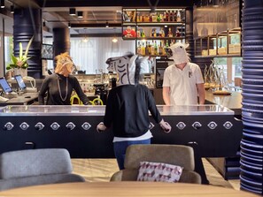 Een bar met een toonbank, krukken en een persoon met een paardenmasker.