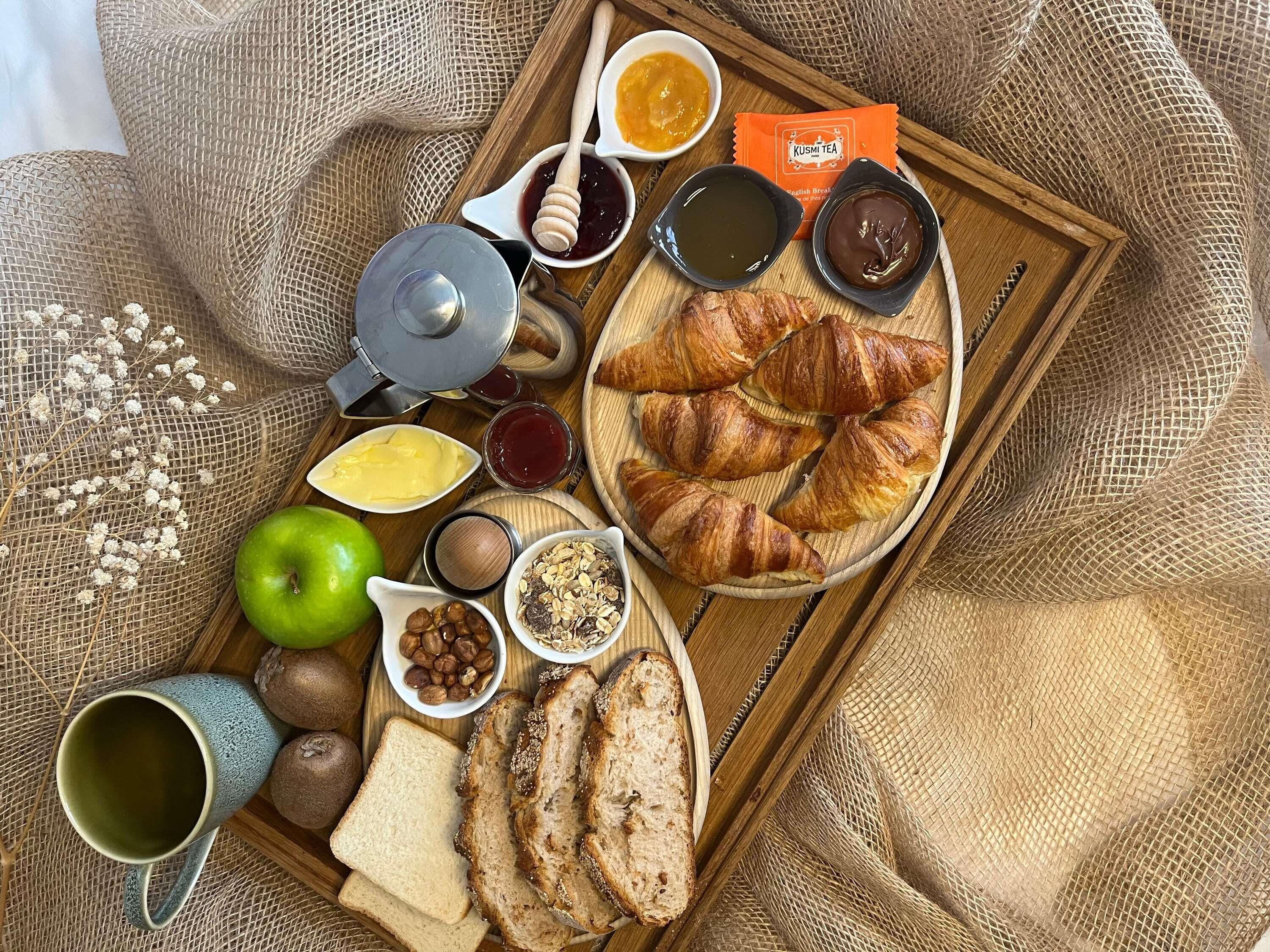 Een ontbijfwagen met croissants, brood, kaas, jam, honing en thee.