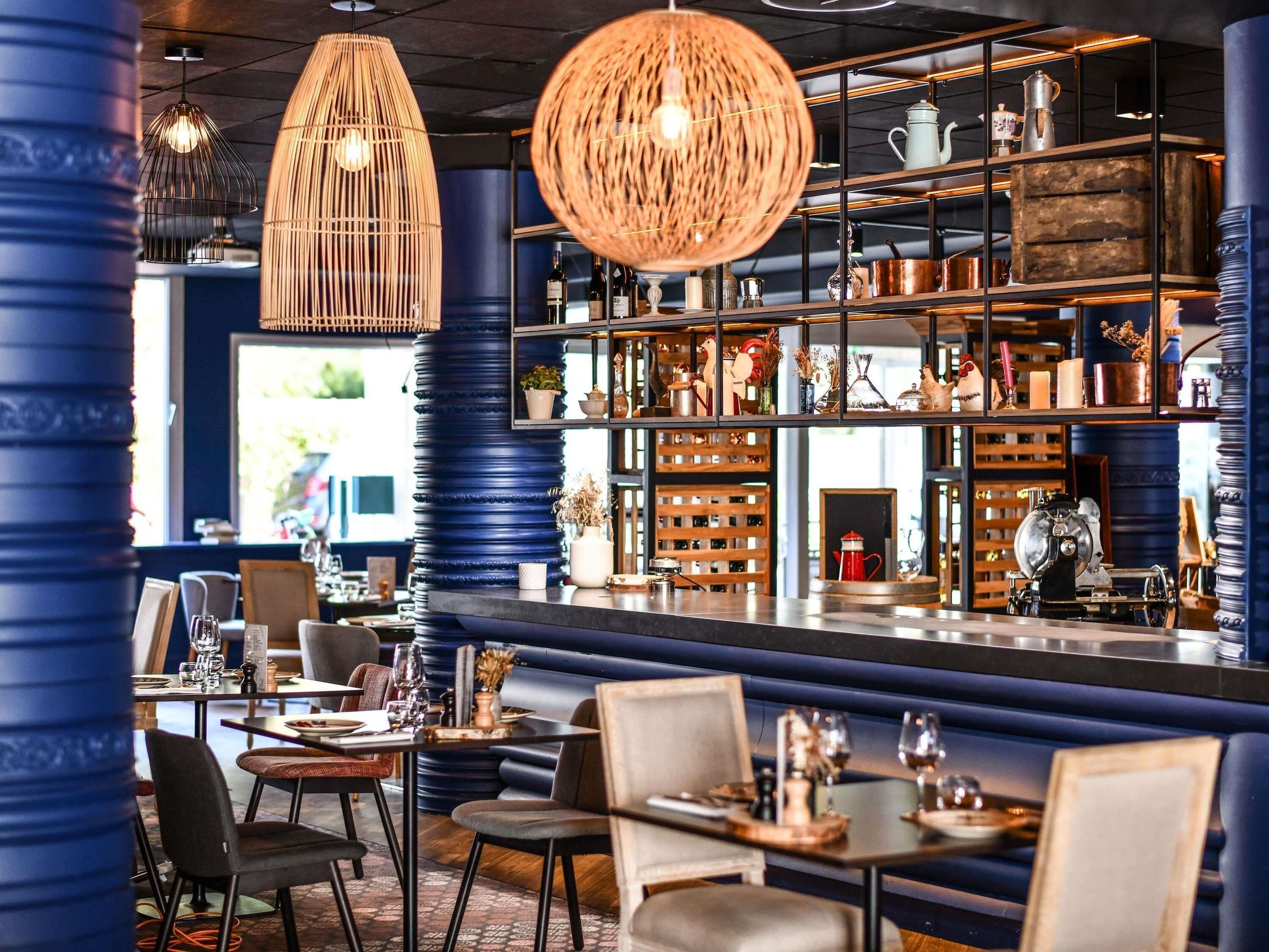 Un restaurant doté d’un bar, de tables et de quelques éléments de décoration disposés sur des étagères.