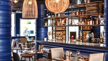 Un restaurant doté d’un bar, de tables et de quelques éléments de décoration disposés sur des étagères.