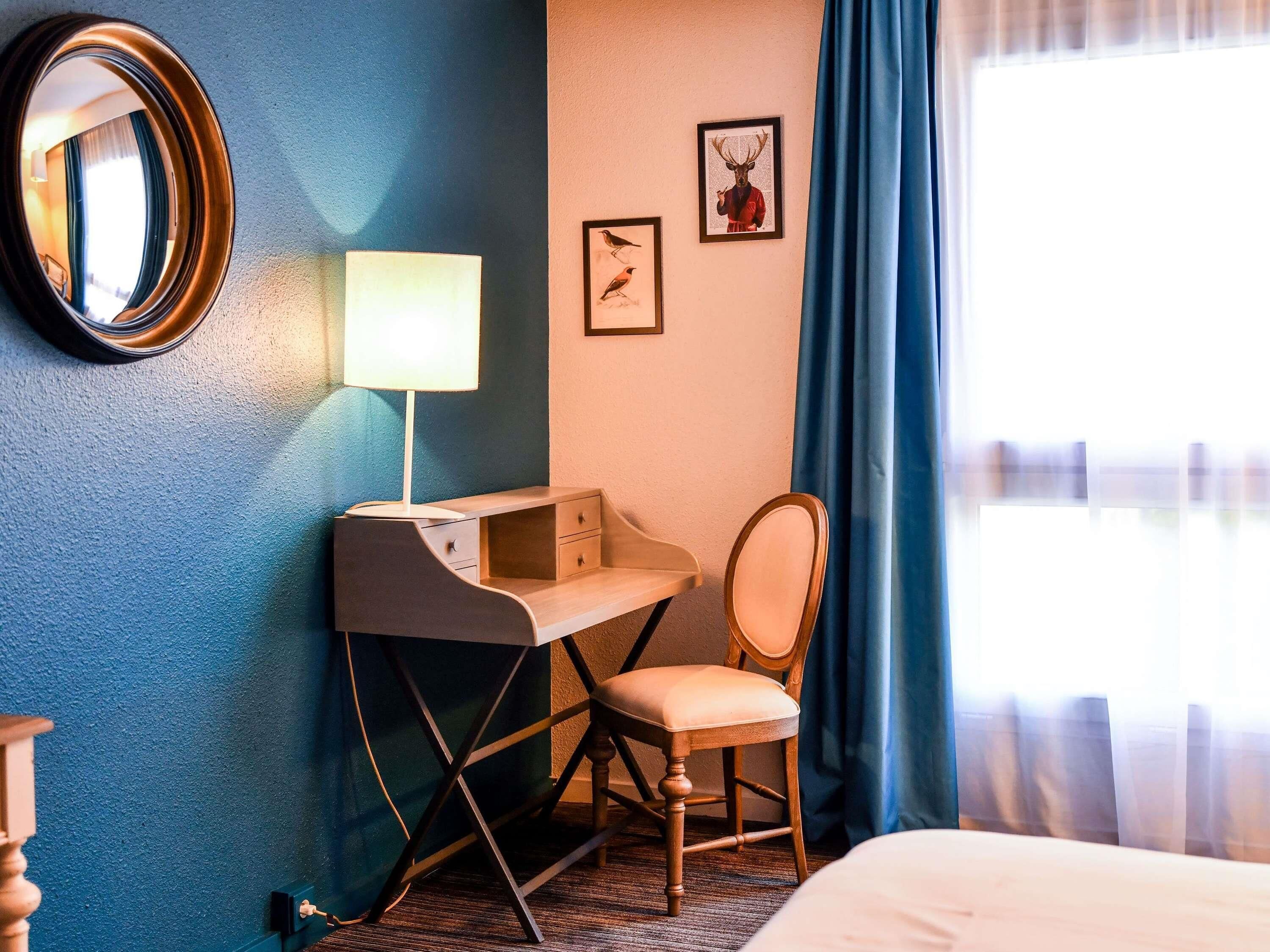 A hotel room with a desk, chair, and a bed.