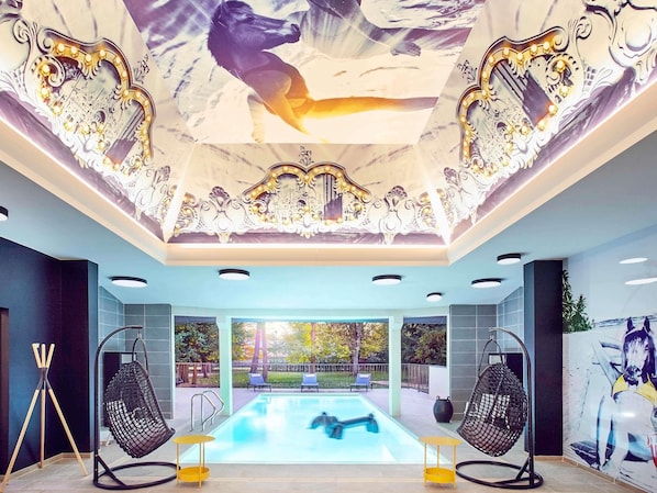 A modern interior with a pool, hanging chairs, and a ceiling with intricate designs.
