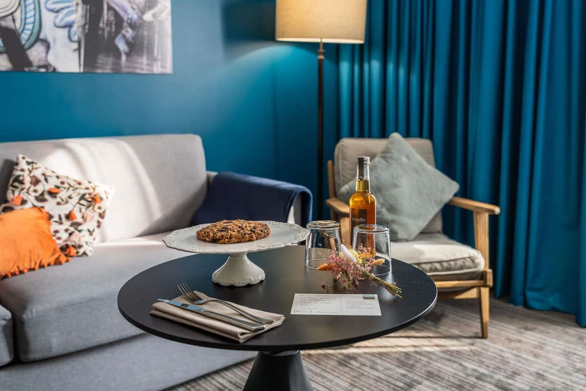 A modern living room with a round table, a sofa, a lamp, and a bottle of liquor.