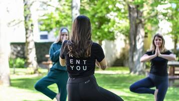 A group of people in a park-like setting, possibly engaged in a yoga or fitness class.
