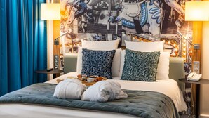 A hotel room with a bed, two pillows, a bedside table with a lamp, and a wall with a mural. - Demeures de campagne Château de Fontainebleau – Mercure (Fontainebleau)