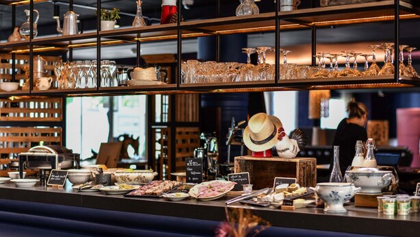 A restaurant counter with various dishes, glasses, and a rooster decoration. - Demeures de campagne Château de Fontainebleau – Mercure (Fontainebleau)