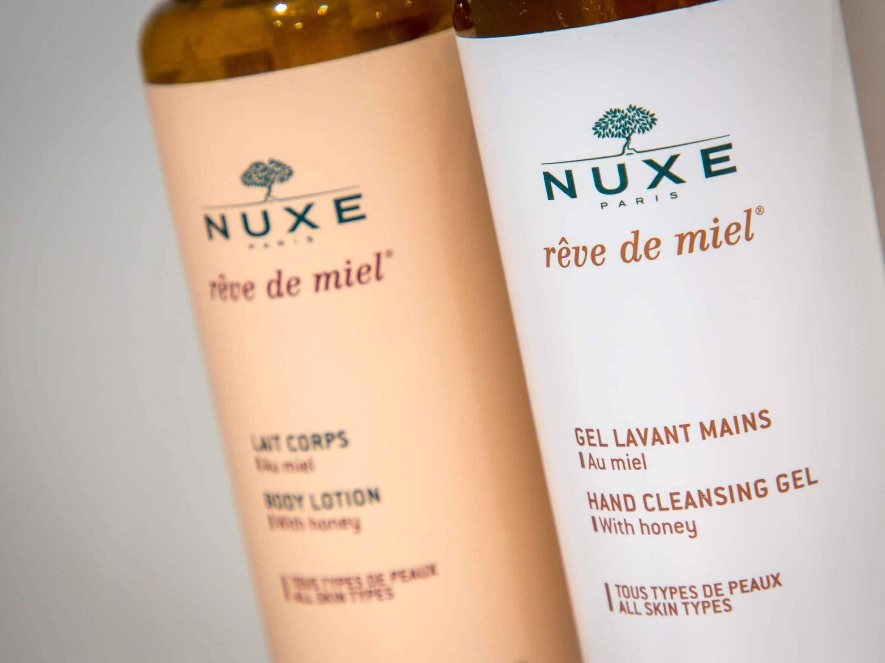 Deux flacons de lotion corporelle Nuxe et un gel nettoyant pour les mains.