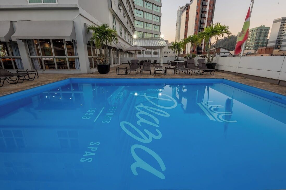 A swimming pool with lounge chairs and potted plants, surrounded by modern buildings.