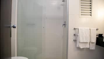 A bathroom with a glass-enclosed shower, a toilet, and a sink with a towel rack.