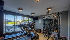 Un gimnasio con cintas de correr, máquinas de pesas y un amplio ventanal con vistas al exterior.