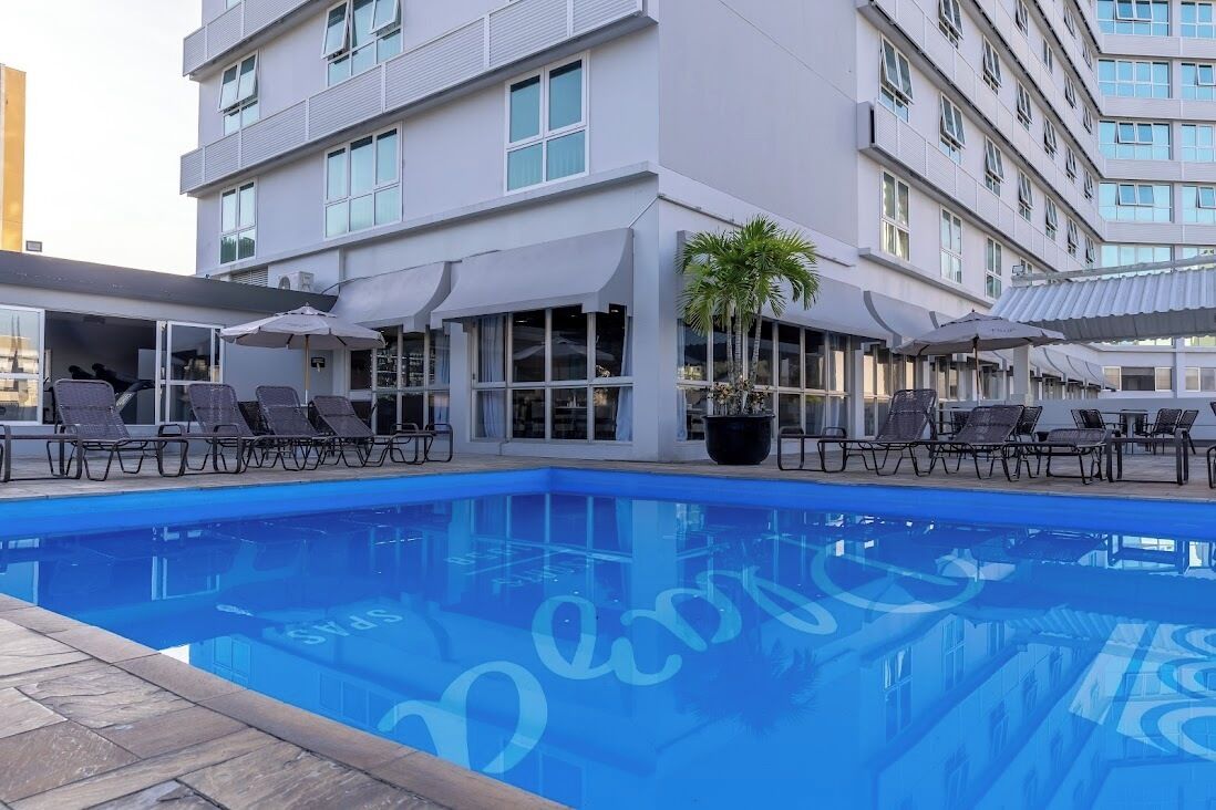 Un hotel moderno con piscina, lettini e ombrelloni.