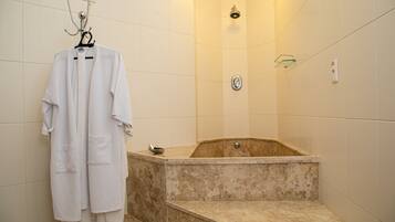 A bathroom with a bathtub, a towel rack with robes, and a showerhead.