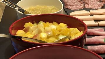 A breakfast buffet with various food items including fruit, yogurt, and meats.