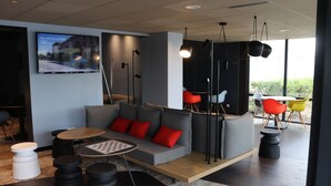 Un espacio lounge moderno con sofá, mesas redondas y sillas coloridas.