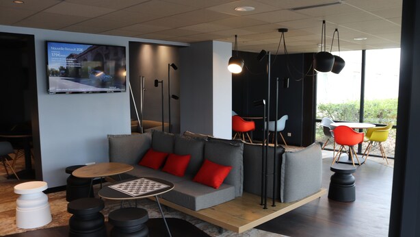 A modern lounge area with a sofa, round tables, and colorful chairs. - ibis Melun Hotel (Melun)