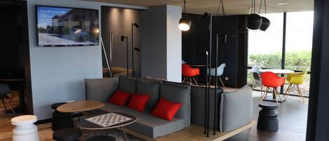 A modern lounge area with a sofa, round tables, and colorful chairs.
