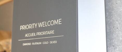A sign with the text "PRIORITY WELCOME" and "ACCUEIL PRIORITAIRE" indicating a priority reception area.
